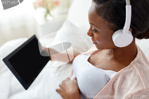 Image of pregnant woman in headphones with tablet pc