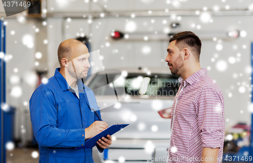 Image of auto mechanic with clipboard and man at car shop