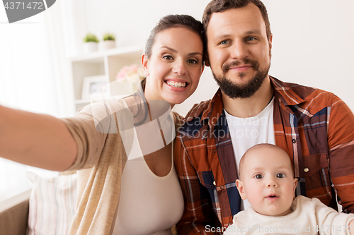 Image of mother and father with baby taking selfie at home