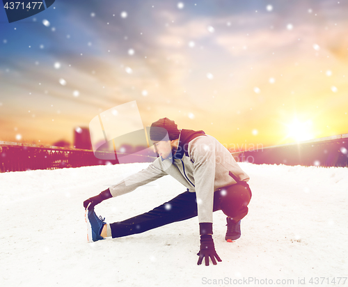 Image of man exercising and stretching leg on winter bridge