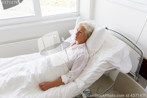 Image of sad senior woman lying on bed at hospital ward