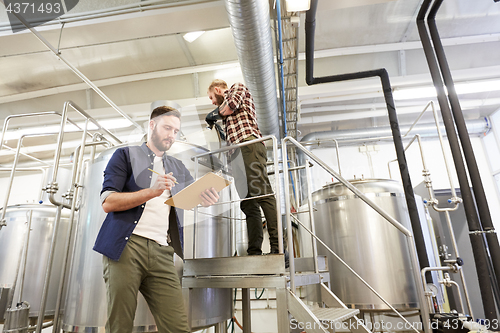 Image of men with clipboard at brewery or beer plant