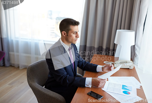 Image of businessman with papers working at hotel room