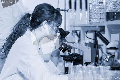Image of Female health care researcher microscoping in scientific laboratory.