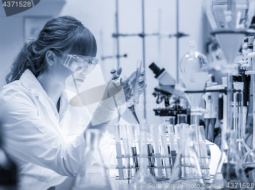 Image of Young scientist pipetting in life science laboratory.