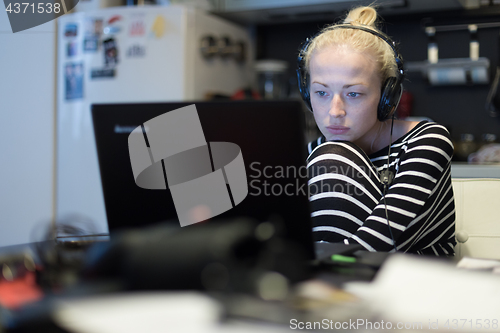 Image of Adult woman in her casual home clothing working and studying remotely from her small flat late at night.