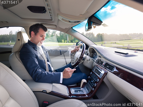 Image of Businessman using cell phone and texting while driving not paying attention to the road.