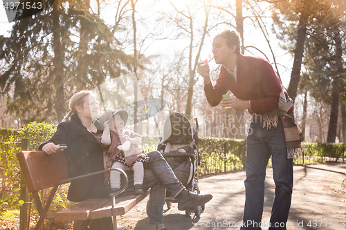 Image of Young family with cheerful child in the park.