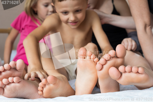 Image of Happy brother and sisters  sitting on the bed barefoot