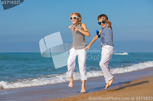 Image of Two happy children playing on the beach at the day time