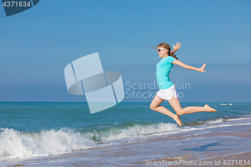 Image of teen girl jumping on the beach at blue sea shore in summer vacat