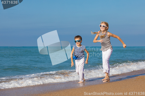 Image of Two happy children playing on the beach at the day time