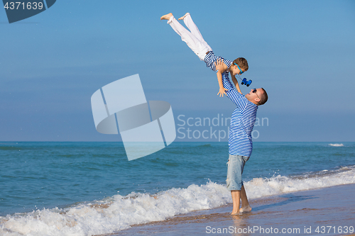 Image of Father and son playing on the beach at the day time. Concept of 