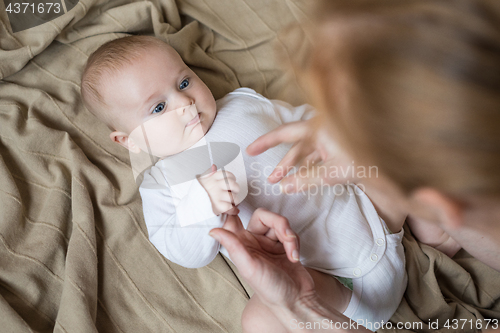 Image of mom dresses the baby on the bed