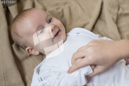 Image of mom dresses the baby on the bed