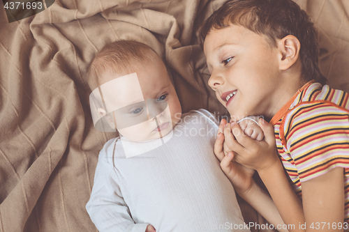 Image of little boy playing with newborn on the bed