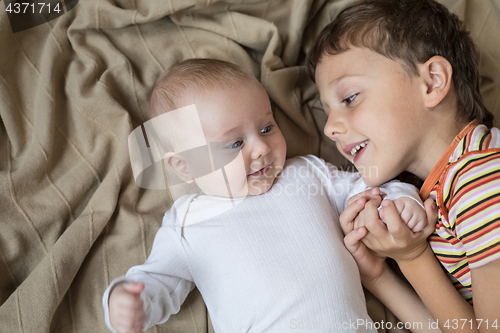 Image of little boy playing with newborn on the bed