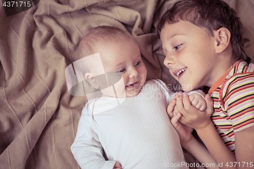 Image of little boy playing with newborn on the bed