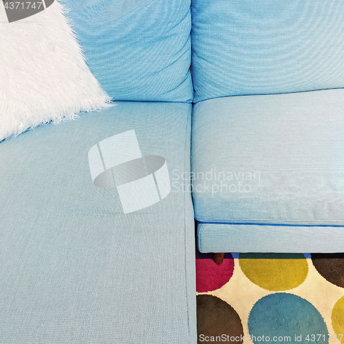 Image of Fluffy white cushion on a blue textile sofa