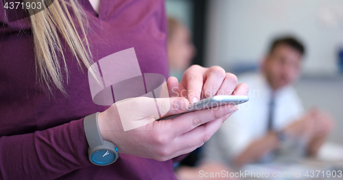 Image of Close up of business woman using cell phone in office interior