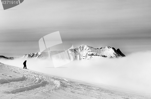 Image of Black and white silhouette of snowboarder on off-piste slope wit
