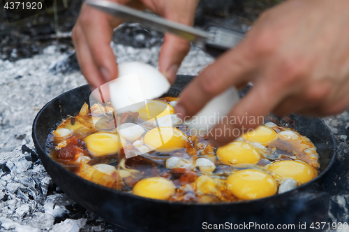 Image of Fried eggs cooking on camp fire in smoke