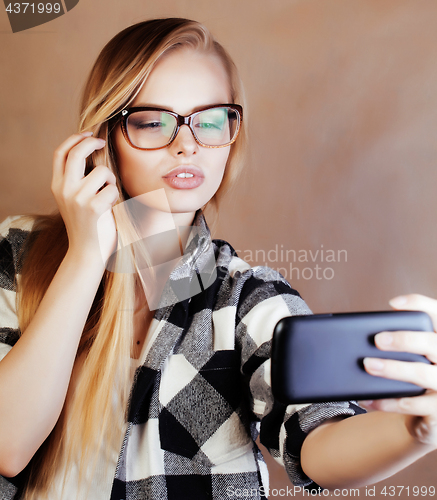 Image of young pretty blond woman with smartphone posing smiling, making 