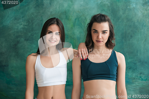 Image of Two young sporty women posing at gym.