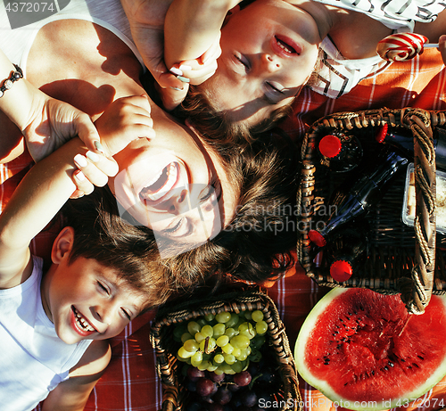 Image of cute happy family on picnic laying on green grass mother and kids, warm summer vacations