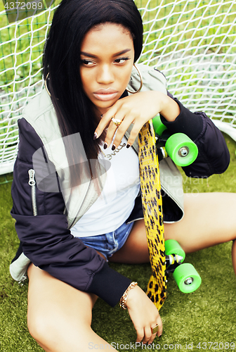Image of cool pretty smiling afro-american happy young woman with skate b