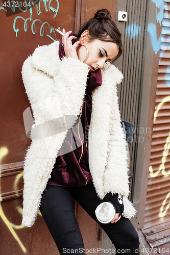 Image of young pretty stylish teenage girl outside in city wall with graf