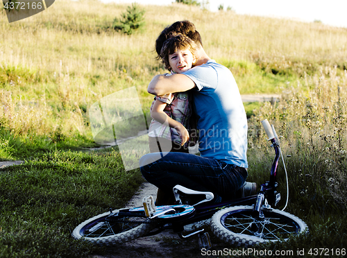 Image of father learning his son to ride on bicycle outside, real happy f