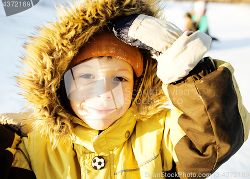 Image of little cute boy in hood with fur on snow outside