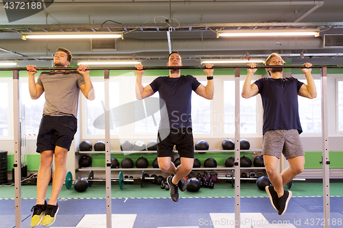 Image of group of young men doing pull-ups in gym