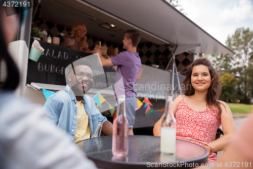 Image of friends with drinks sitting at table at food truck