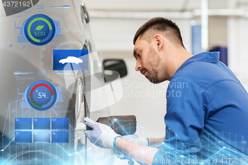 Image of mechanic with screwdriver changing car tire