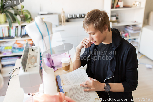 Image of fashion designer reading book at studio