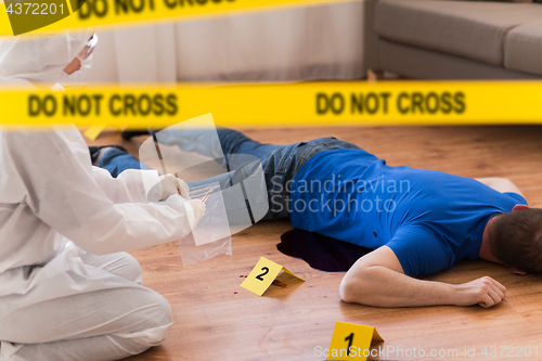 Image of criminalist collecting evidence at crime scene