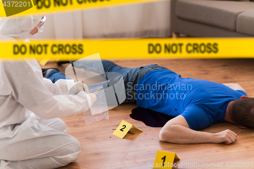 Image of criminalist collecting evidence at crime scene