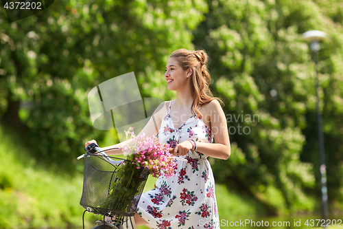 Image of happy woman riding fixie bicycle in summer park