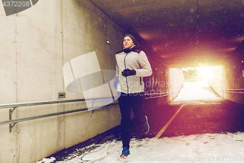 Image of happy man running along subway tunnel in winter