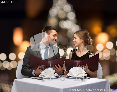 Image of smiling couple with menus at christmas restaurant