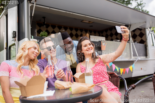 Image of happy young friends taking selfie at food truck