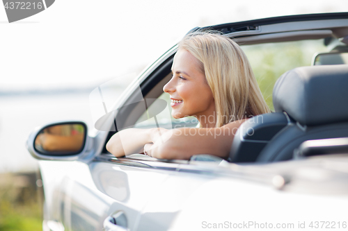 Image of happy young woman in convertible car