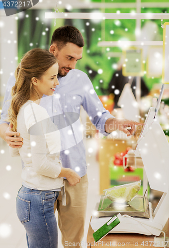 Image of happy couple weighing cabbage on scale at grocery