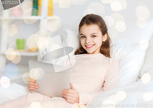 Image of happy girl in bed with tablet pc over lights