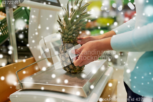 Image of customer with pineapple on scale at grocery store