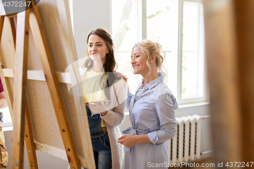 Image of artists discussing painting on easel at art school