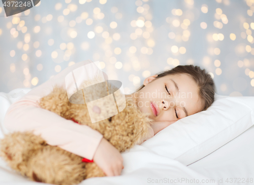 Image of girl sleeping with teddy bear toy in bed