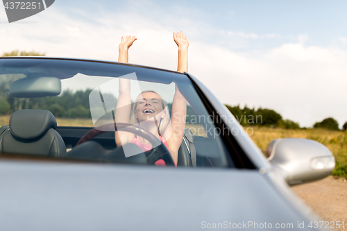 Image of happy young woman in convertible car